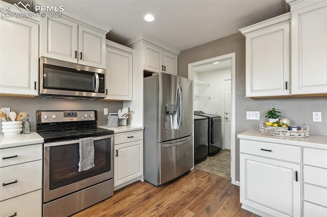 8463 Shadow Run Ln, Fountain, CO 80817 - kitchen featuring stainless steel appliances, separate washer and dryer, dark wood finished floors, light countertops, and white cabinetry