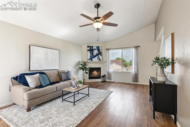 8463 Shadow Run Ln, Fountain, CO 80817 - living room with lofted ceiling, wood-type flooring, a ceiling fan, a lit fireplace, and baseboards