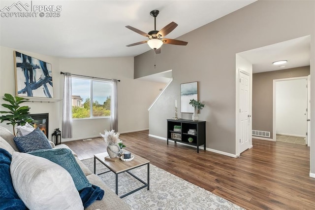 8463 Shadow Run Ln, Fountain, CO 80817 - living area featuring vaulted ceiling, ceiling fan, wood finished floors, baseboards, and a glass covered fireplace