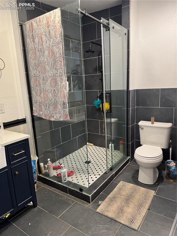 1005 S Cascade Ave, Colorado Springs, CO 80903 - bathroom featuring a stall shower, toilet, tile patterned floors, vanity, and tile walls