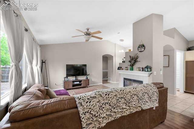 629 Golden Eagle Dr, Colorado Springs, CO 80916 - living area featuring arched walkways, vaulted ceiling, ceiling fan, a tile fireplace, and light wood finished floors