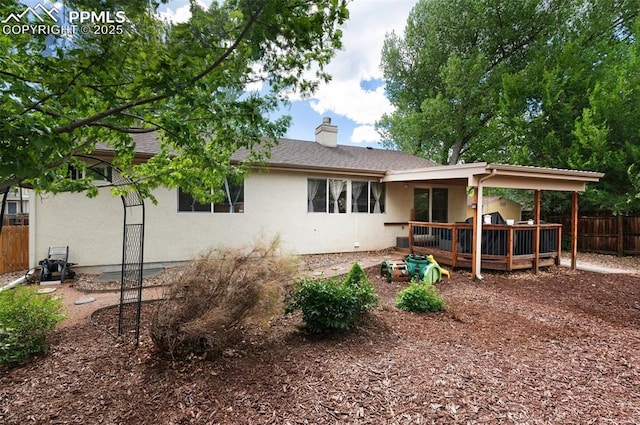 629 Golden Eagle Dr, Colorado Springs, CO 80916 - back of house with fence, stucco siding, a wooden deck, a chimney, and roof with shingles