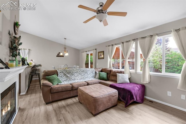 629 Golden Eagle Dr, Colorado Springs, CO 80916 - living area featuring light wood-style flooring, lofted ceiling, ceiling fan, a glass covered fireplace, and baseboards