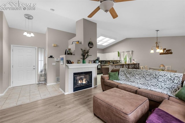 629 Golden Eagle Dr, Colorado Springs, CO 80916 - living room with vaulted ceiling, a ceiling fan, light wood finished floors, a chandelier, and a tile fireplace