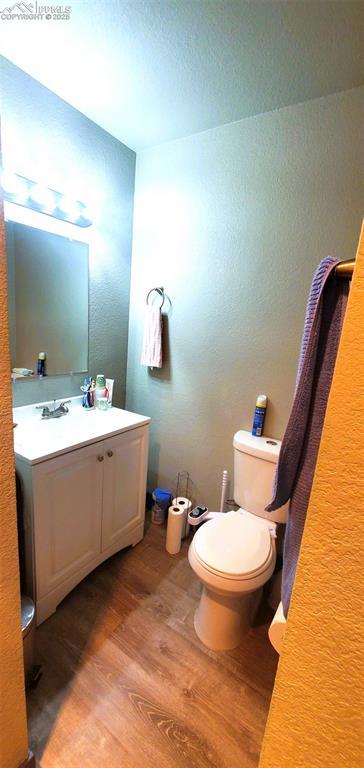 4406 Teeter Totter Way, Colorado Springs, CO 80917 - bathroom featuring wood finished floors, toilet, vanity, and a textured wall