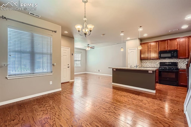 8883 White Prairie Vw, Colorado Springs, CO 80924 - kitchen with black appliances, a chandelier, decorative backsplash, wood finished floors, and recessed lighting