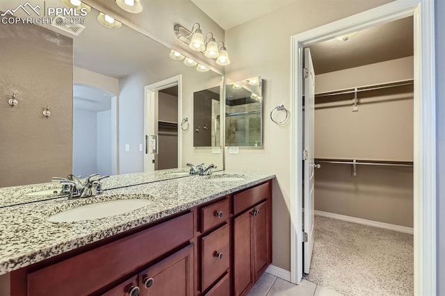 8883 White Prairie Vw, Colorado Springs, CO 80924 - bathroom with double vanity, a spacious closet, tile patterned flooring, and baseboards