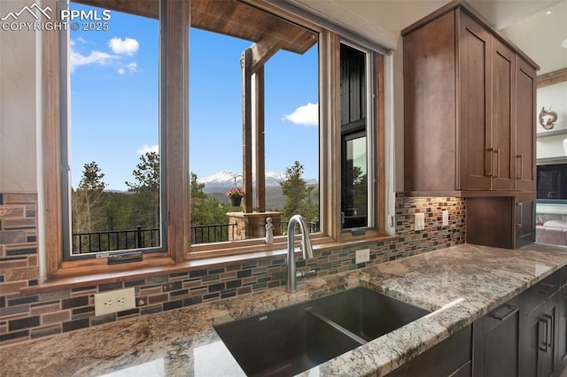 kitchen with a sink, decorative backsplash, and light stone counters