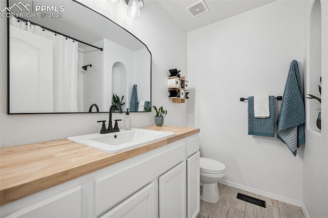 bathroom featuring toilet, baseboards, vanity, and a shower with shower curtain