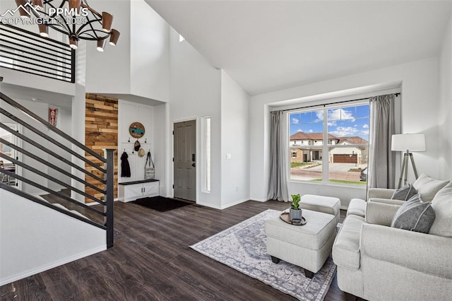 living area with high vaulted ceiling, a chandelier, stairway, baseboards, and wood finished floors