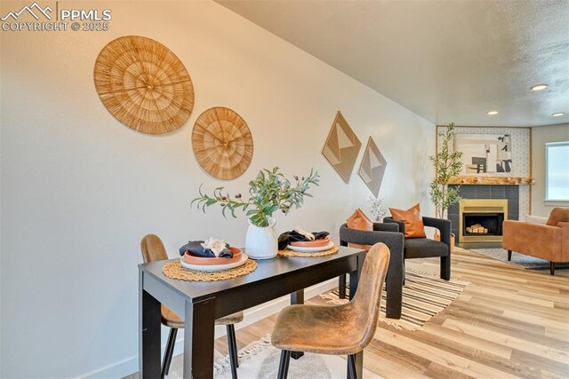 1228 Soaring Eagle Dr, Colorado Springs, CO 80915 - dining space featuring wood finished floors, a tiled fireplace, recessed lighting, and baseboards