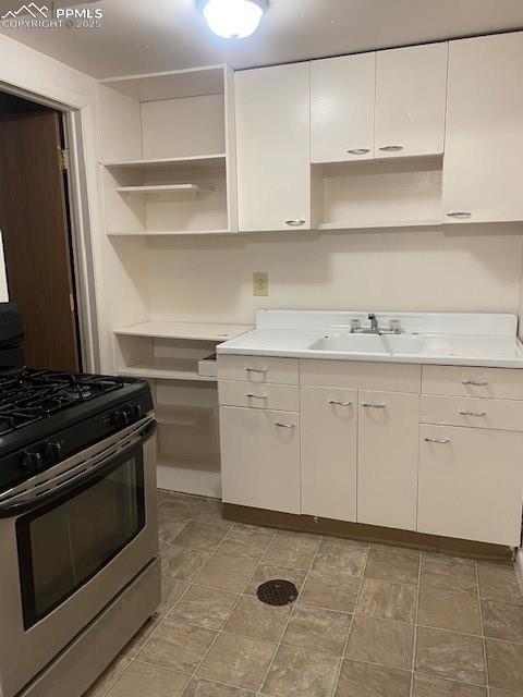 909 E Costilla St, Colorado Springs, CO 80903 - kitchen with stainless steel gas range oven, open shelves, a sink, white cabinets, and light countertops