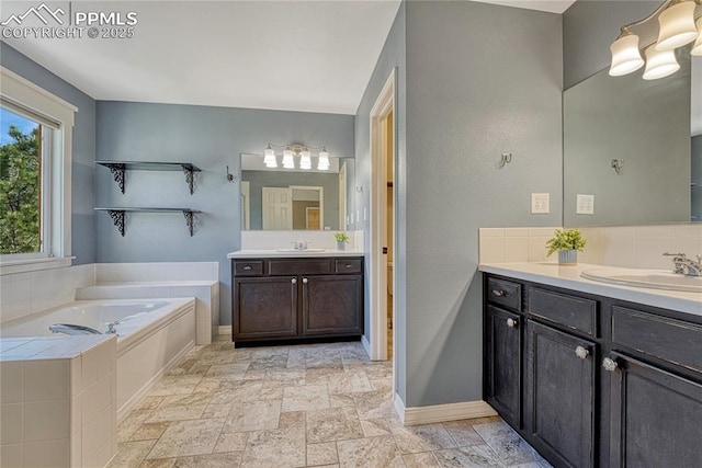 2044 Coldstone Way, Colorado Springs, CO 80921 - full bath with two vanities, a bath, baseboards, and stone tile flooring