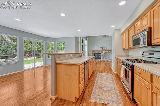 9524 Pinebrook Way, Colorado Springs, CO 80920 - kitchen with stainless steel appliances, light wood-style floors, a stone fireplace, recessed lighting, and light countertops