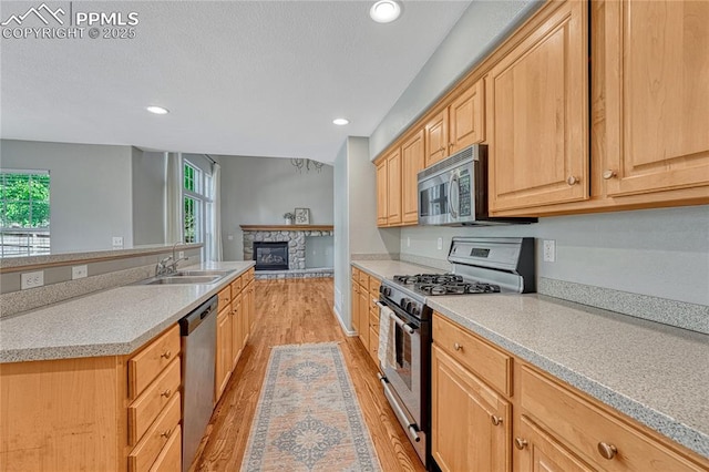 9524 Pinebrook Way, Colorado Springs, CO 80920 - kitchen with appliances with stainless steel finishes, light wood-style floors, light brown cabinetry, a fireplace, and recessed lighting