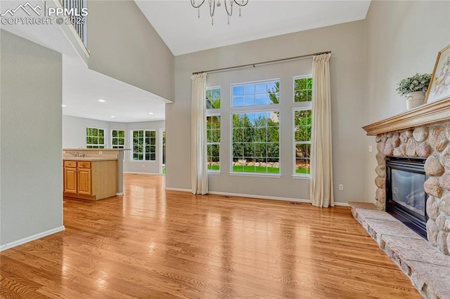 9524 Pinebrook Way, Colorado Springs, CO 80920 - unfurnished living room featuring light wood-type flooring, a fireplace, a chandelier, baseboards, and a sink