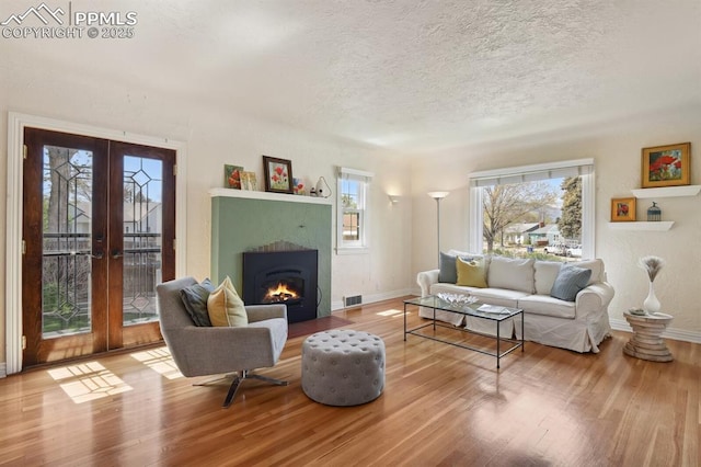 1003 N Institute St, Colorado Springs, CO 80903 - living area featuring wood finished floors, french doors, a textured ceiling, baseboards, and a tiled fireplace