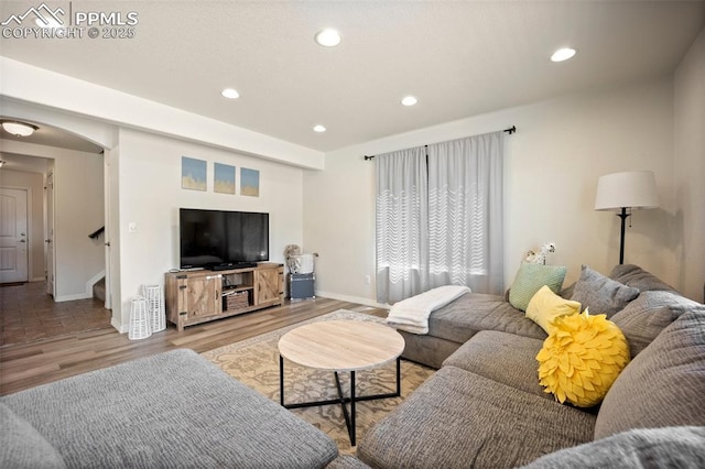 living room with baseboards, wood finished floors, stairway, arched walkways, and recessed lighting
