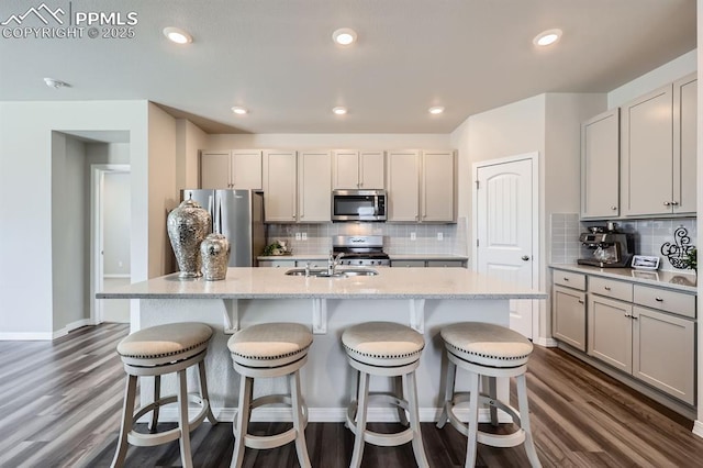 10737 Rolling Mesa Dr, Falcon, CO 80831 - kitchen with stainless steel appliances, dark wood finished floors, tasteful backsplash, an island with sink, and recessed lighting