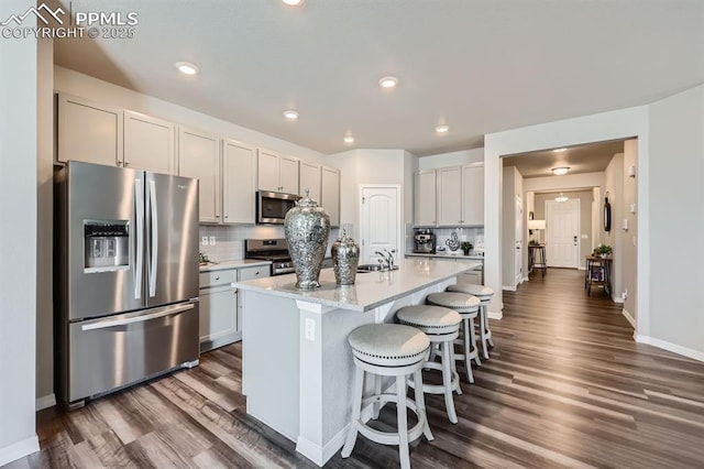 10737 Rolling Mesa Dr, Falcon, CO 80831 - kitchen featuring stainless steel appliances, dark wood-type flooring, a breakfast bar, tasteful backsplash, and recessed lighting