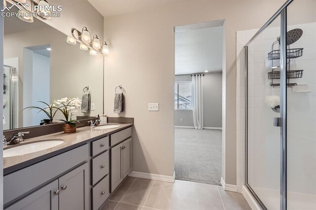 10737 Rolling Mesa Dr, Falcon, CO 80831 - bathroom featuring a shower stall, baseboards, double vanity, and tile patterned floors