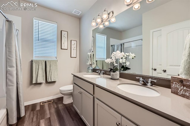 10737 Rolling Mesa Dr, Falcon, CO 80831 - full bath with baseboards, wood finished floors, a shower with shower curtain, toilet, and double vanity