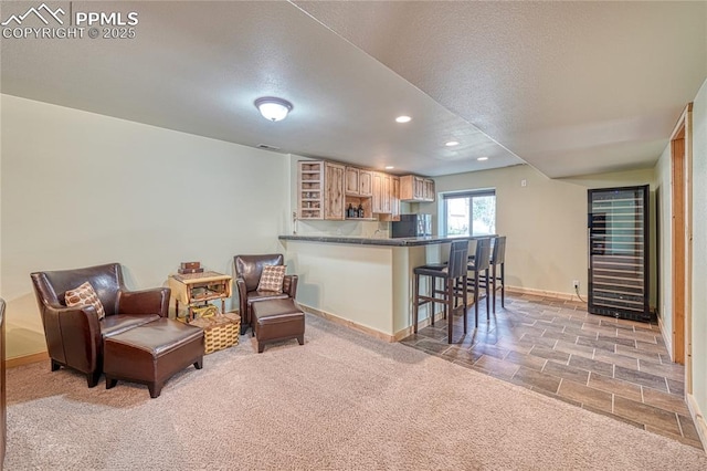 kitchen featuring wine cooler, a breakfast bar, light brown cabinetry, baseboards, and recessed lighting