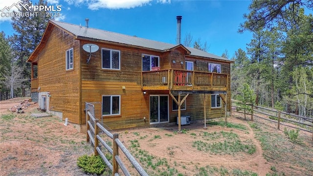 back of house featuring fence and metal roof