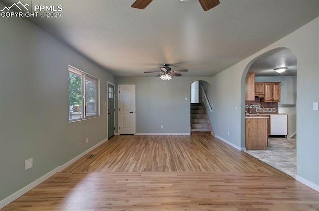 98 Security Cir, Colorado Springs, CO 80911 - unfurnished living room featuring ceiling fan, light wood-style floors, arched walkways, and baseboards