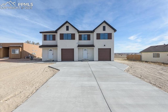 view of front of property featuring concrete driveway, a garage, stucco siding, and fence