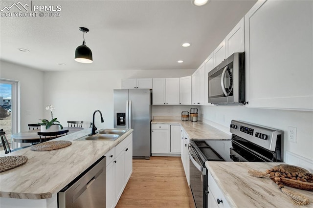 kitchen featuring stainless steel appliances, a sink, recessed lighting, white cabinets, and a kitchen island with sink
