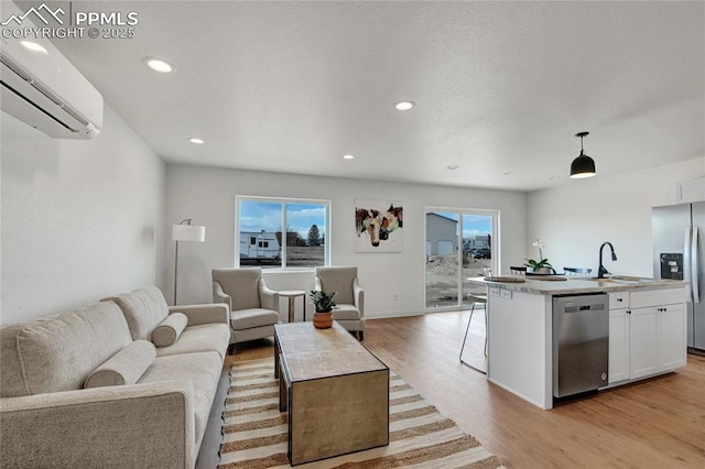living area with an AC wall unit, light wood-style flooring, recessed lighting, and baseboards