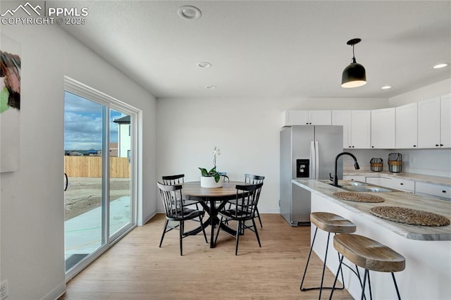 dining room featuring light wood finished floors, recessed lighting, and baseboards