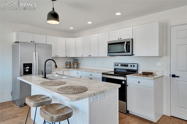 kitchen featuring appliances with stainless steel finishes, a sink, white cabinets, light wood-style floors, and recessed lighting