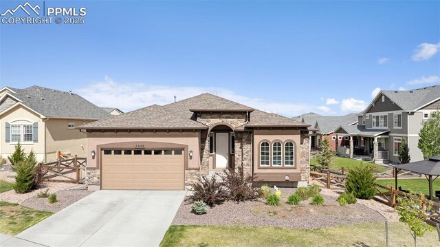 6949 Compass Bend Dr, Colorado Springs, CO 80927 - view of front of property with stone siding, an attached garage, concrete driveway, and stucco siding
