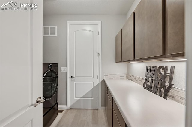 6949 Compass Bend Dr, Colorado Springs, CO 80927 - washroom featuring cabinet space, light wood-style flooring, washer / clothes dryer, and baseboards