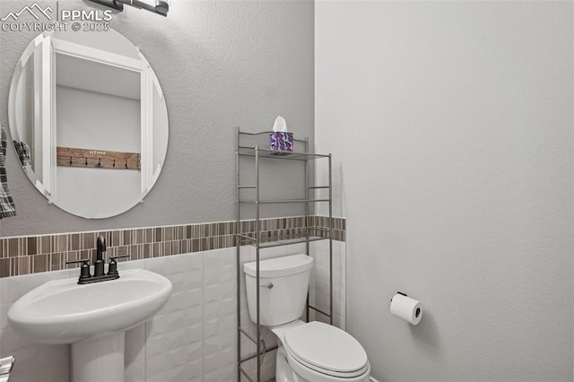 6949 Compass Bend Dr, Colorado Springs, CO 80927 - half bathroom featuring toilet, tile walls, and a sink