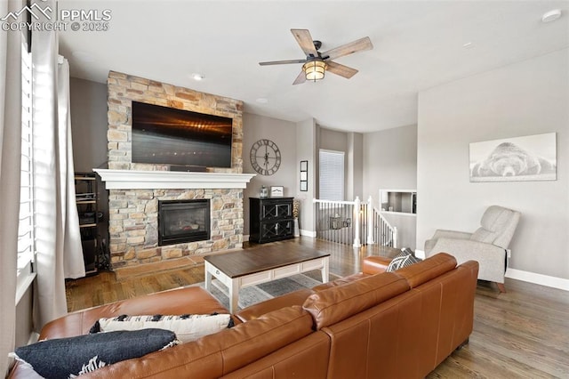 444 Pasada Way, Monument, CO 80132 - living room with wood finished floors, ceiling fan, baseboards, and a stone fireplace