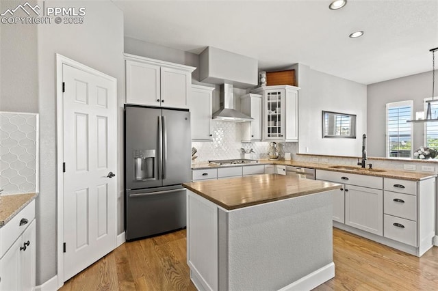 444 Pasada Way, Monument, CO 80132 - kitchen featuring appliances with stainless steel finishes, wall chimney exhaust hood, a sink, a peninsula, and light wood-type flooring