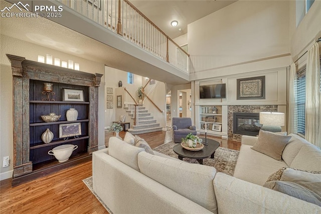15872 Maple Hill Rd, Monument, CO 80132 - living area featuring a towering ceiling, wood finished floors, stairs, a premium fireplace, and plenty of natural light