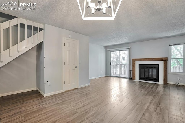514 Shady Crest Cir, Colorado Springs, CO 80916 - unfurnished living room with a textured ceiling, wood finished floors, a chandelier, a glass covered fireplace, and baseboards