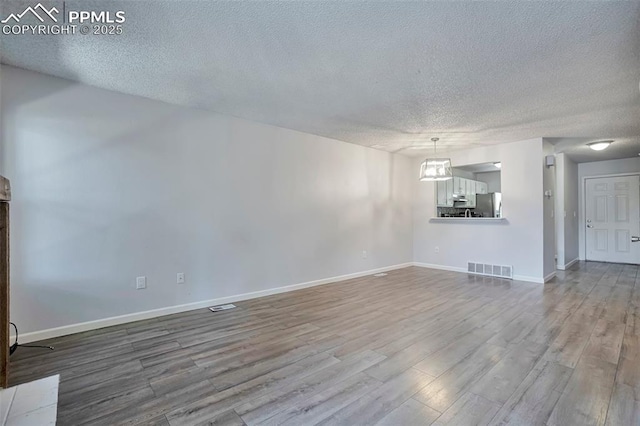 514 Shady Crest Cir, Colorado Springs, CO 80916 - unfurnished living room with a textured ceiling, wood finished floors, and baseboards