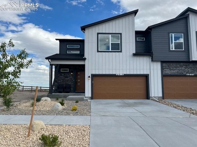 6913 Knapp Dr, Colorado Springs, CO 80924 - contemporary home with board and batten siding, an attached garage, driveway, a porch, and stone siding