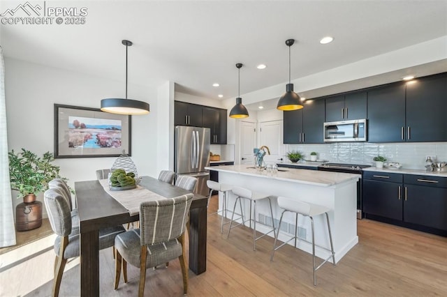 6913 Knapp Dr, Colorado Springs, CO 80924 - kitchen featuring stainless steel appliances, a breakfast bar, backsplash, a sink, and hanging light fixtures