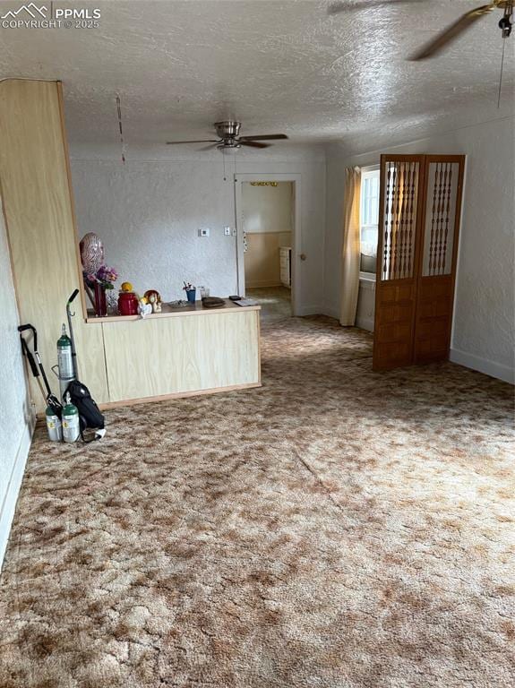 2531 Gunnison St, Colorado Springs, CO 80909 - unfurnished living room with ceiling fan, a textured ceiling, a textured wall, carpet, and baseboards