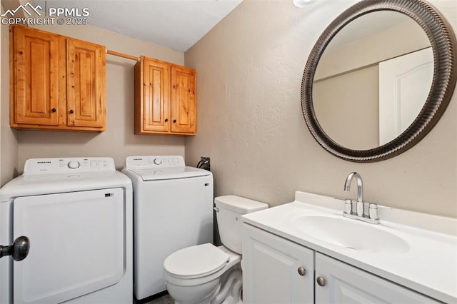 bathroom featuring washing machine and clothes dryer, toilet, and vanity