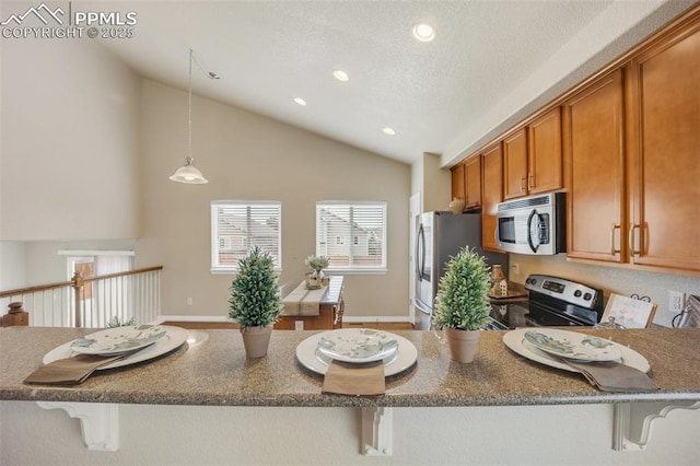 6259 Bearcat Loop, Colorado Springs, CO 80925 - kitchen featuring stainless steel appliances, a kitchen breakfast bar, recessed lighting, brown cabinets, and dark stone counters