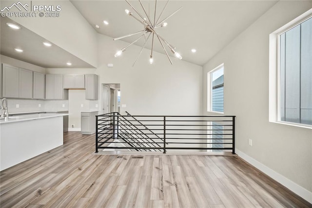 3065 Curly Grv, Colorado Springs, CO 80922 - unfurnished living room featuring a chandelier, light wood-style flooring, recessed lighting, baseboards, and a sink