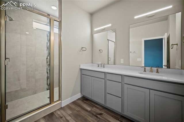 3065 Curly Grv, Colorado Springs, CO 80922 - full bathroom with a stall shower, wood finished floors, double vanity, and baseboards