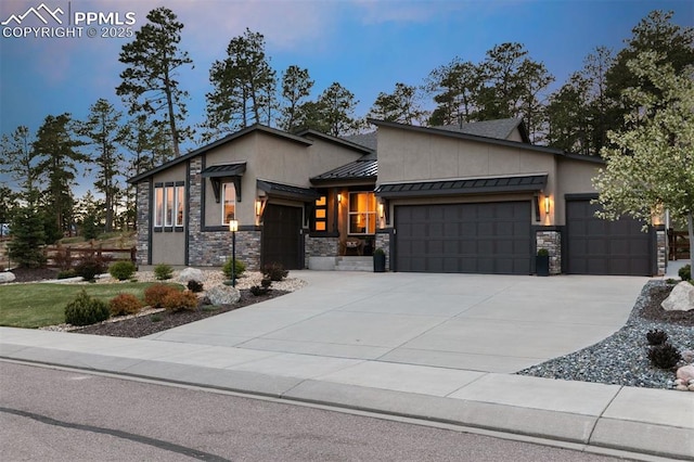 16244 Thunder Cat Way, Monument, CO 80132 - modern home featuring an attached garage, a standing seam roof, stone siding, and concrete driveway